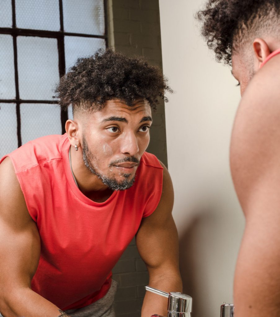 Homme qui se regarde dans le miroir avec de la crème sur le visage