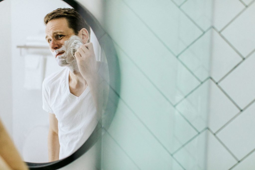 Homme qui se met de la mousse à raser avec un blaireau